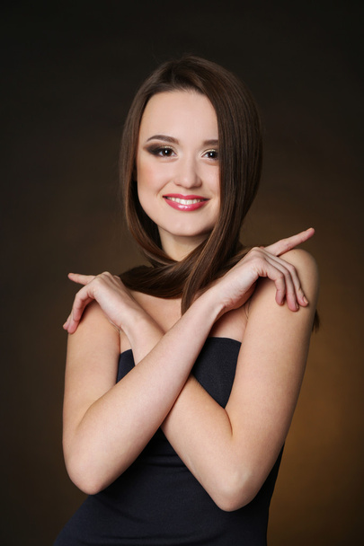 Beautiful young woman with long hair on dark brown background - Fotó, kép