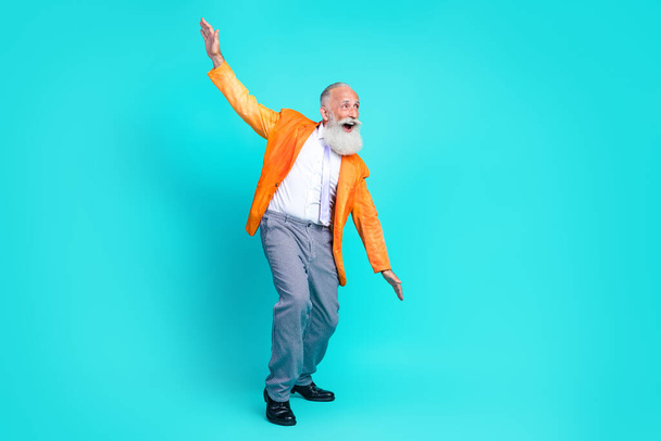 Full length photo of cheerful cute pensioner guy wear neon orange jacket dancing disco having fun isolated teal color background. - Zdjęcie, obraz