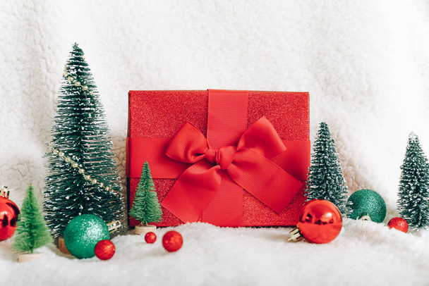 Cadeau rouge, sapins et décorations sur fond plaid blanc - Photo, image
