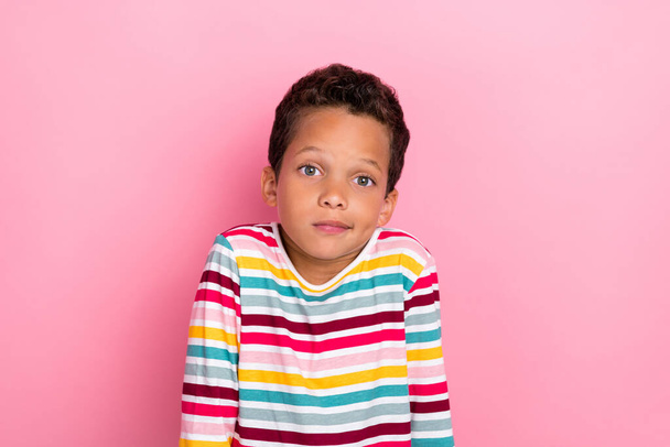 Portrait of nice adorable schoolboy with wavy hairdo wear striped long sleeve confused look at camera isolated on pink color background. - Foto, afbeelding