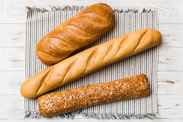Válogatás frissen sült kenyér szalvétával rusztikus asztal tetejére. Egészséges kovásztalan kenyér. Francia kenyér. - Fotó, kép