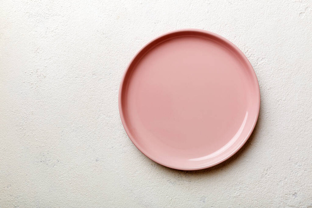 Вид зверху на порожню рожеву тарілку на цементному фоні. Порожнє місце для вашого дизайну
. - Фото, зображення