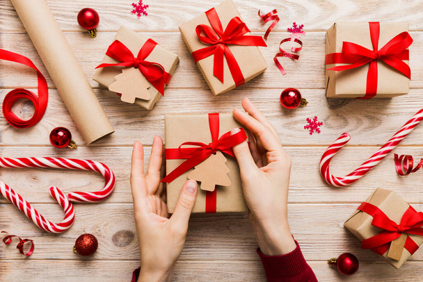 Kadın eli hediye kutusunu tutuyor, sürprizi hazırlıyor, üst manzara, Noel ve yeni yıl konsepti. - Fotoğraf, Görsel