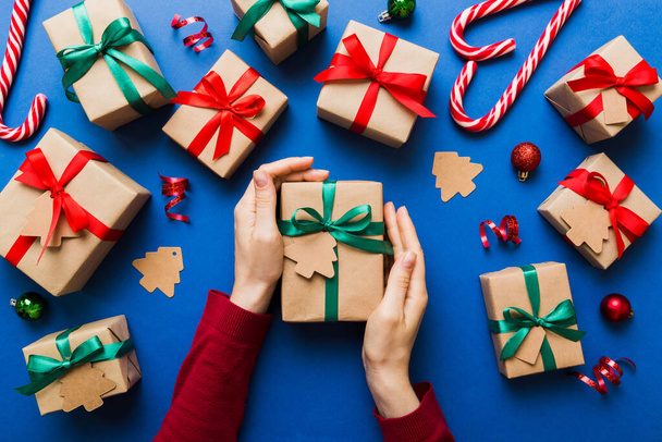 Жінка тримає коробку з подарунками, готуючи сюрприз для відпочинку, зверху, Різдво та Новий рік.. - Фото, зображення