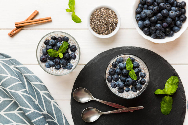 Healthy breakfast or morning with chia seeds vanilla pudding and blueberry berries on table background, vegetarian food, diet and health concept. Chia pudding with coconut milk and blueberry. - Foto, Imagem