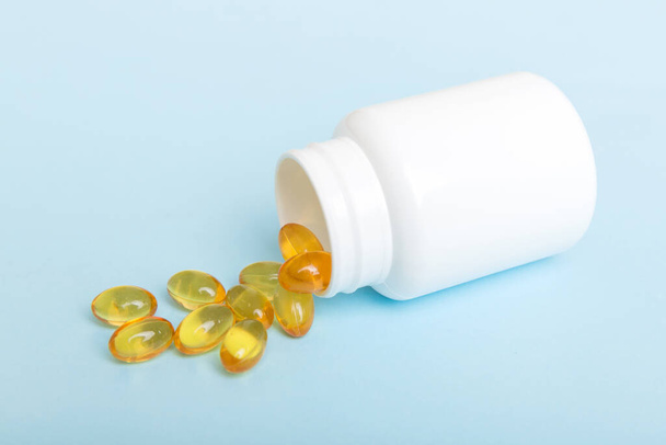 Omega-3 kapselit ovat valkoisessa pullossa pöydällä taustalla. Kalaöljy tabletit ylhäältä näkymä. Biologisesti aktiiviset lisäaineet. omega 6, omega 9, A-vitamiini, E-vitamiini, D-vitamiini, D3-vitamiini, iltaruusuöljy. - Valokuva, kuva