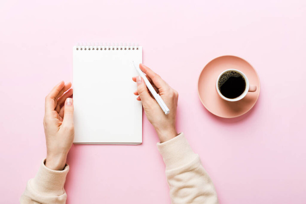 Žena ruka s tužkou psaní na notebook a podržte šálek kávy. Žena pracující na kancelářském stole s kávou. - Fotografie, Obrázek