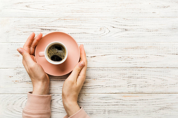 Minimalistische stijl vrouw hand met een kopje koffie op gekleurde achtergrond. Platte lay, bovenaanzicht cappuccino cup. Lege plek voor tekst, kopieer ruimte. Koffie verslaving. Bovenaanzicht, vlak lay. - Foto, afbeelding