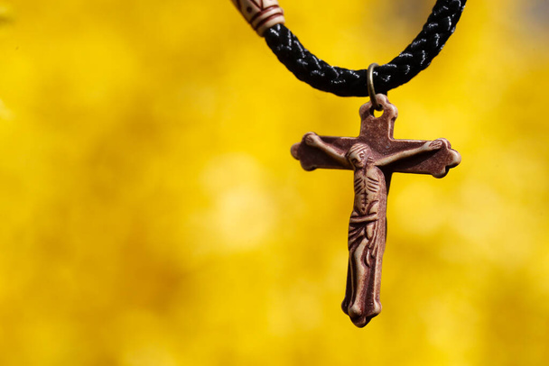 Jesus Christ pendant against yellow broom flowers.  - Фото, зображення