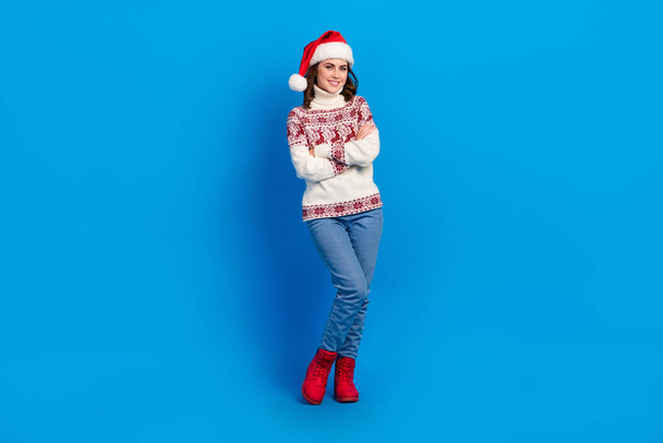 Photo of funky charming young girl dressed print sweater claus cap smiling arms folded isolated blue color background. - Foto, immagini