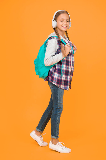 hipster girl care backpack. schoolgirl casual style hold school bag. autumn kid fashion. child listen music headset. childhood education and development. happy childrens day. audio book. - Foto, imagen