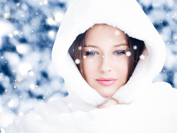 Felices fiestas, estilo de vida y moda de invierno, hermosa mujer con abrigo de piel esponjosa blanca, nevando nieve en la naturaleza del bosque nevado como Navidad, Año Nuevo y estilo de retrato de vacaciones - Foto, imagen