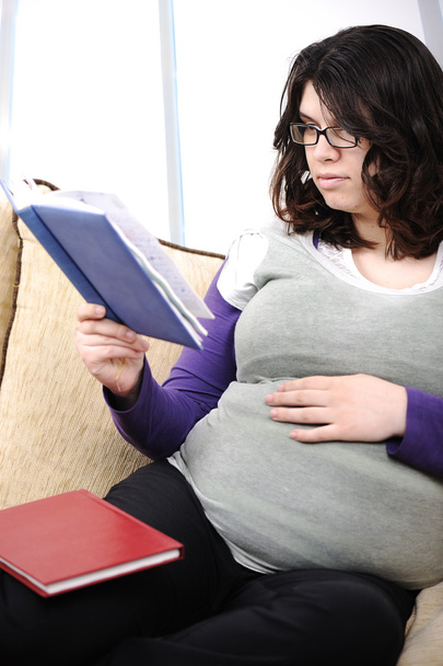 9 months pregnant woman sitting on sofa and reading book - Φωτογραφία, εικόνα