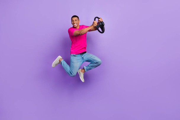 Full length portrait of energetic overjoyed man jumping arms hold wheel isolated on purple color background. - Foto, Bild