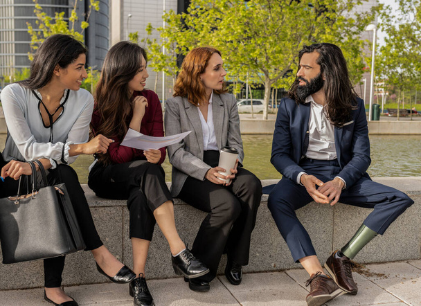 Fiatal nők és férfi műlábbal vitatkoznak az irodán kívül - Fotó, kép