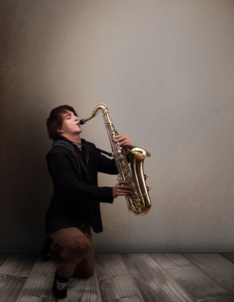 Young musician playing on saxophone - Foto, Imagen