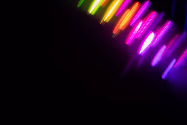 Verschwommenes Licht beim Malen einer Belichtung in der Kamera. Licht leuchtet mit einem spektralen Gradienten auf dunklem Hintergrund. Bunte abstrakte farbenfrohe Linie. Ungewöhnlicher Lichteffekt. - Foto, Bild