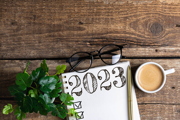 New year resolutions 2023 on desk. 2023 resolutions list with notebook, coffee cup on table. Goals, resolutions, plan, action, checklist concept. New Year 2023 background. Copy spac - Фото, зображення