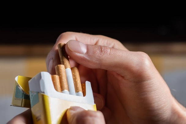 close up man hand holding peel it off cigarette pack prepare smoking a cigarette. Packing line up - Photo, image