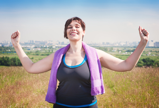 幸せなプラスサイズの女性空に腕を上げる成功  - 写真・画像