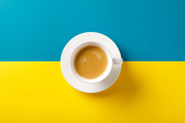 Black coffee in a cup on Ukraine flag blue and yellow background. - Fotoğraf, Görsel