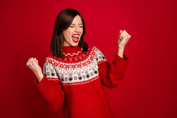 Portrait of excited satisfied woman with bob hairdo wear red sweater eyes closed raise fists scream yeah isolated on red color background. - Φωτογραφία, εικόνα