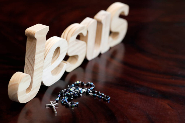 木製の文字はイエスとロザリオという言葉を形成します。キリスト教のシンボル.  - 写真・画像