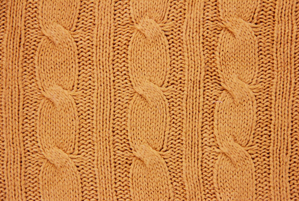 η υφή ενός πορτοκαλί μάλλινου υφάσματος πλεκτού από νήματα με μοτίβο κοτσίδας - Φωτογραφία, εικόνα