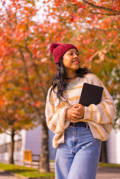 Asian girl walking in autumn with a tablet in her hand, technology concept - Foto, immagini