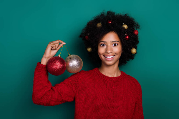 Photo portrait of nice pupil girl holding new year tree decoration balls wear trendy red knitted clothes isolated on green color background. - Photo, image