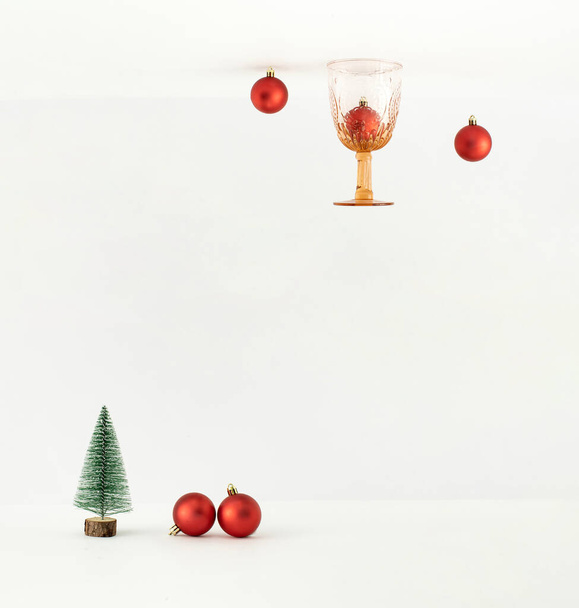 Perspectiva de cabeça para baixo com bugigangas de Natal, vidro de beber vintage e árvore no fundo branco. Conceito mínimo de Ano Novo. - Foto, Imagem