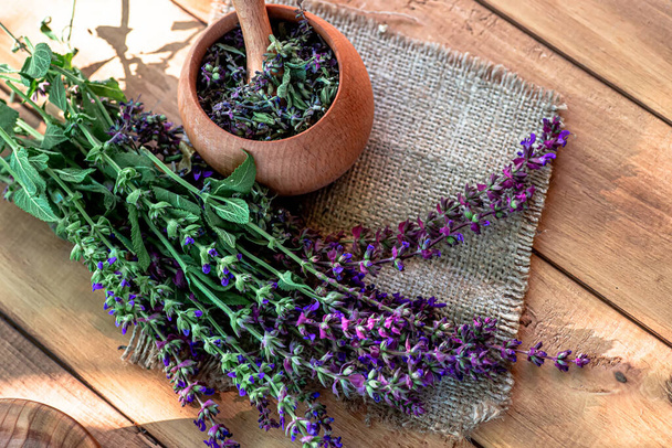 薬や薬のチンキのための準備ができて乾燥した花とモルタル近くの木製の田舎のテーブルの上のセージの花 - 写真・画像