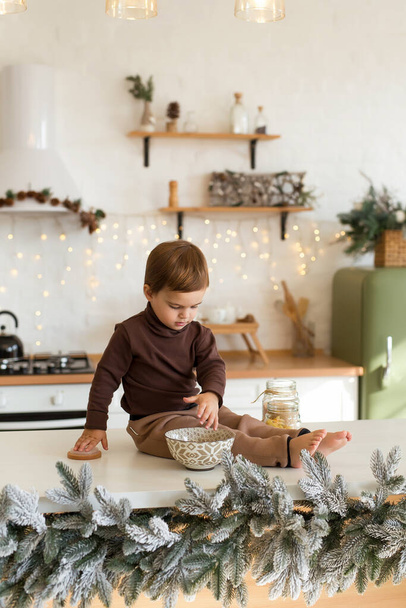 Portrait of toddler boy playing and having fun at Christmas decorated kitchen. Happy kid waiting for the holidays. Vertical photo - Φωτογραφία, εικόνα