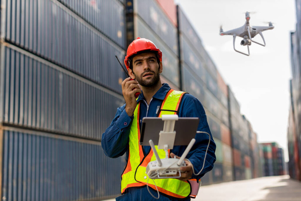 Foreman or worker use remote controller piloting drone at containers port for checking container. Foreman use remote control Drone with camera flying on container cargo ship at shipping port. - Photo, Image
