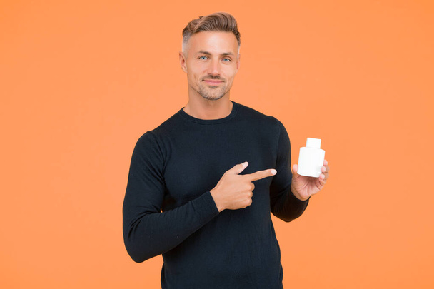 Handsome guy in casual style point index finger presenting mens perfumery product for grooming and personal care yellow background, pointing. - Φωτογραφία, εικόνα
