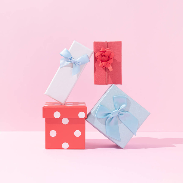 Christmas gifts creative composition. Red and blue present boxes against pastel pink background. Happy Christmas or New Year concept. Minimal holidays celebration aesthetic. - Photo, Image