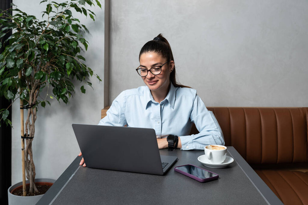 Young business woman freelancer financial expert using her lunch and coffee break to talk about work with his happy satisfied client on video call on laptop. Businessperson conversation office team - Фото, зображення