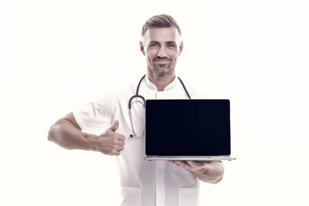 man therapist with laptop. medical worker with stethoscope show thumb up. technology in modern medicine. make an appointment with doctor online. physician consultation on covid. Your personal account. - 写真・画像