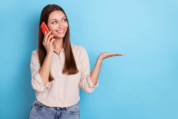 Photo of charming positive person lady speak phone modern devise 5g look demonstrate empty space isolated on blue color background. - Fotografie, Obrázek