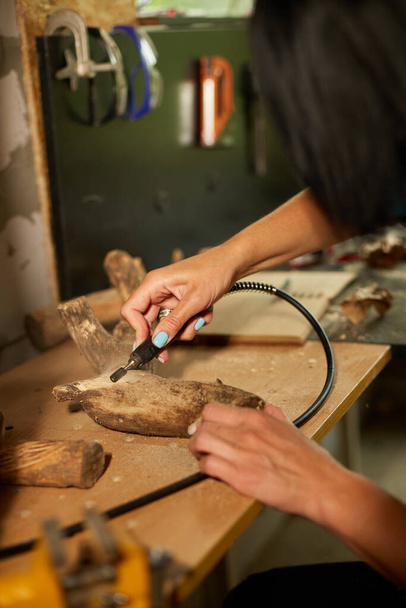 木彫りの工具を使った女性の彫刻、手作りのお土産の製作、ワークショップでの女性. - 写真・画像