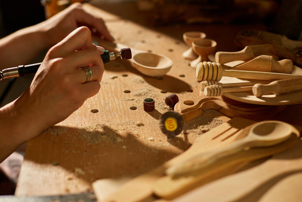Hembra usando herramientas de trabajo de energía graver para utensilios de madera cuchara, tallado, amoladora durante la elaboración, creación de recuerdos artesanales hechos a mano, mujer en el taller. - Foto, Imagen