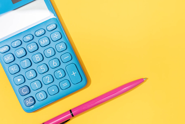 Плоский шар калькулятора і ручки на жовтому тлі. Яскраві кольори Копіювання простору
 - Фото, зображення