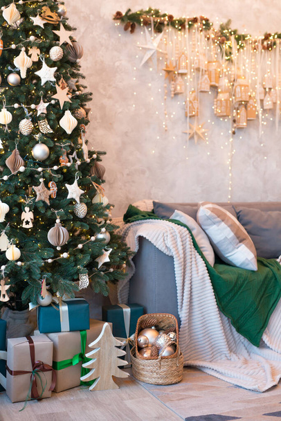 Belső tér modern stúdió nappali kényelmes kanapéval díszített karácsonyfák és ajándékok. Függőleges kép - Fotó, kép