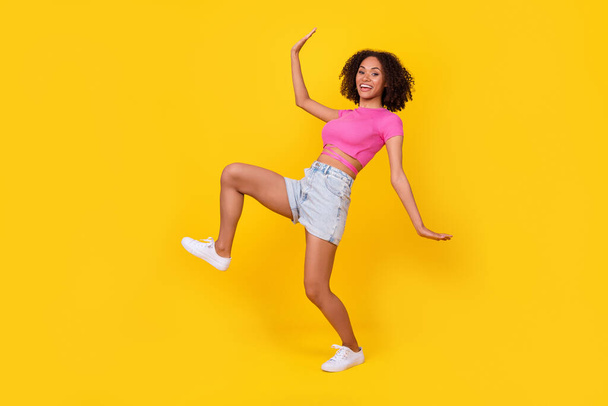 Full size profile photo of positive crazy girl have good mood sneaky walk isolated on yellow color background. - Foto, Imagem