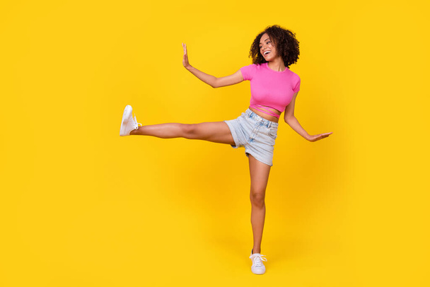Full body photo of playful cheerful girl have fun raise one leg dancing isolated on yellow color background. - Photo, Image