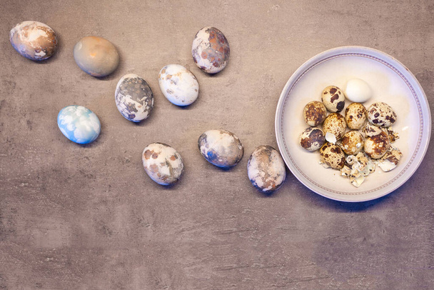 paaseieren op beton. Happy Easter kaart: marmeren steen effect geschilderd met lege ruimte voor tekst. bowl bovenaanzicht, kwarteleitjes plat leggen - Foto, afbeelding