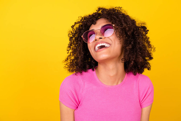 Foto von verträumt aufgeregt Dame tragen rosa Top dunkle Brille lachen suchen leeren Raum isoliert gelbe Farbe Hintergrund. - Foto, Bild