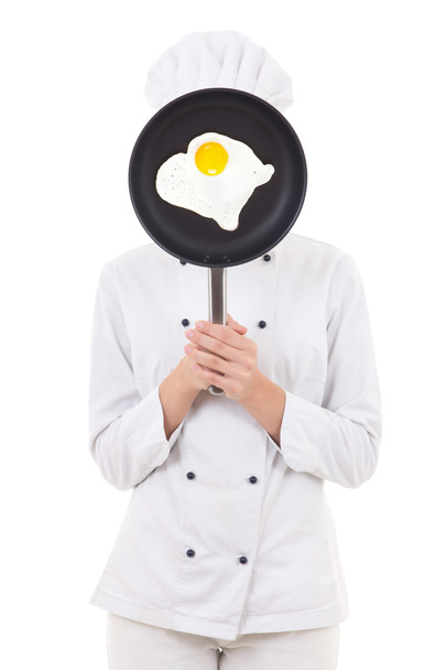 mujer joven en sartén de explotación uniforme de chef con freír huevo behi - Foto, imagen