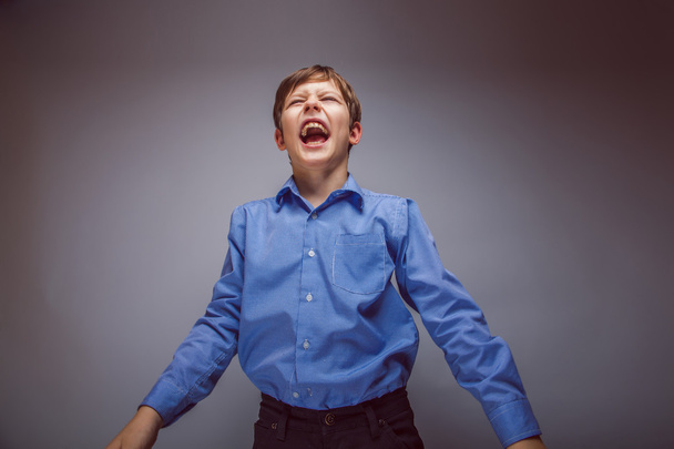 Portrait of a boy brown European appearance shouting on gray bac - Photo, Image