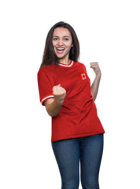 Young beautiful fan in a red t-shirt of the Canada national team celebrating a goal happy and excited on white background. - Foto, Imagem